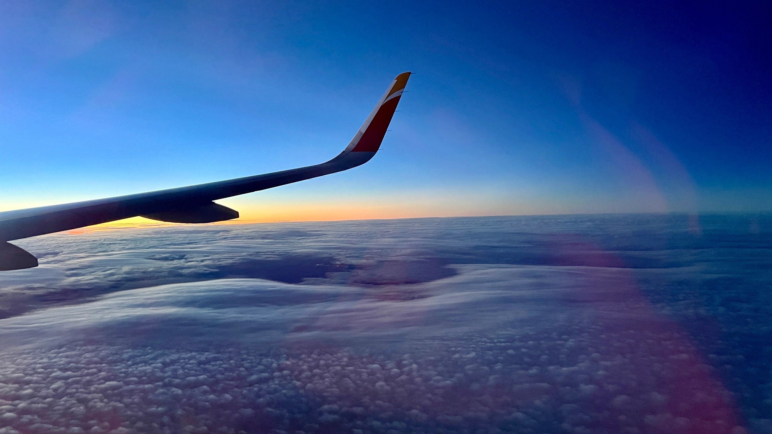 Airplane wing above clouds at sunset
